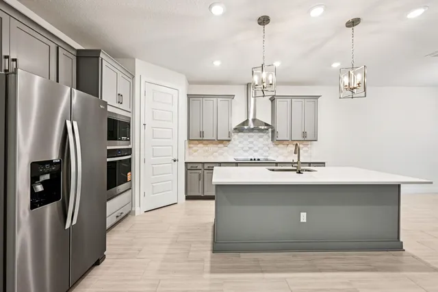 a kitchen with stainless steel appliances granite countertop a refrigerator a sink and a stove