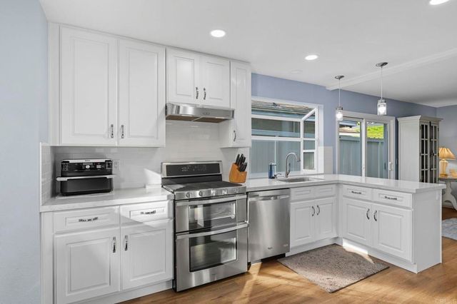 a kitchen with stainless steel appliances granite countertop a stove and white cabinets
