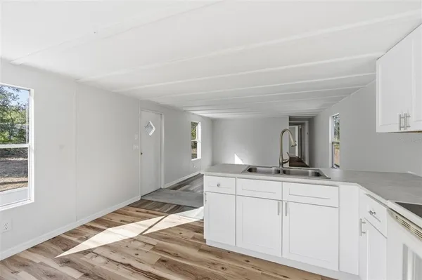a hallway with granite countertop white cabinets and window