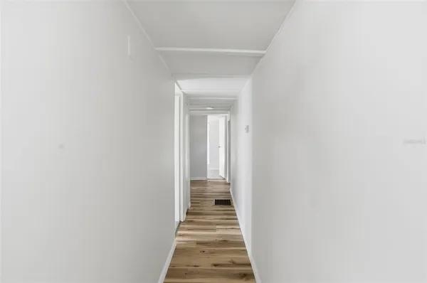 a view of a hallway with a white door and wooden floor