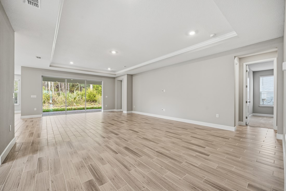 86049 Living Waters Run Yulee, FL 32097 - Photo 8 of 36 a view of an empty room with wooden floor and windows