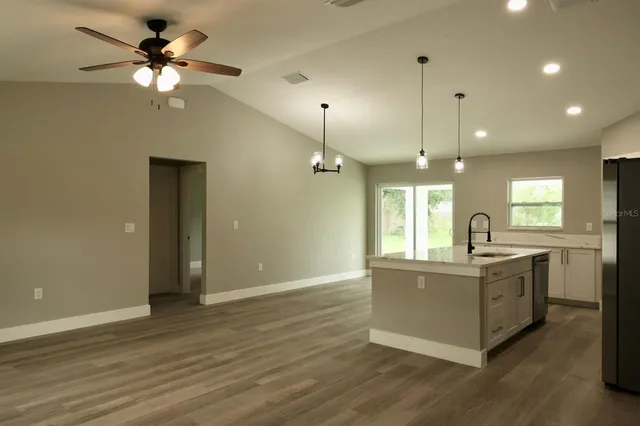a view of a kitchen counter space a sink wooden floor and a ceiling fan