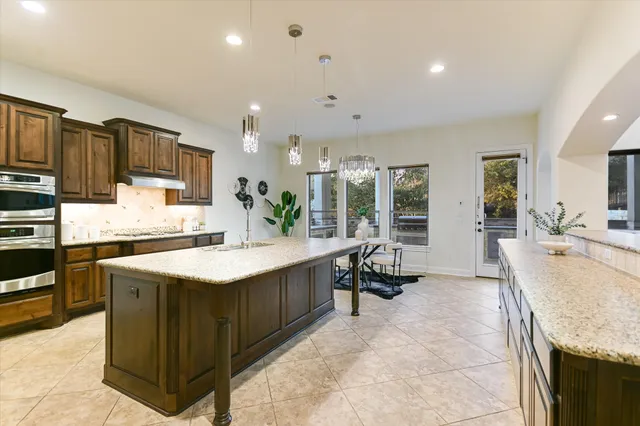 a kitchen with stainless steel appliances granite countertop a sink dishwasher and a dining table with wooden floor