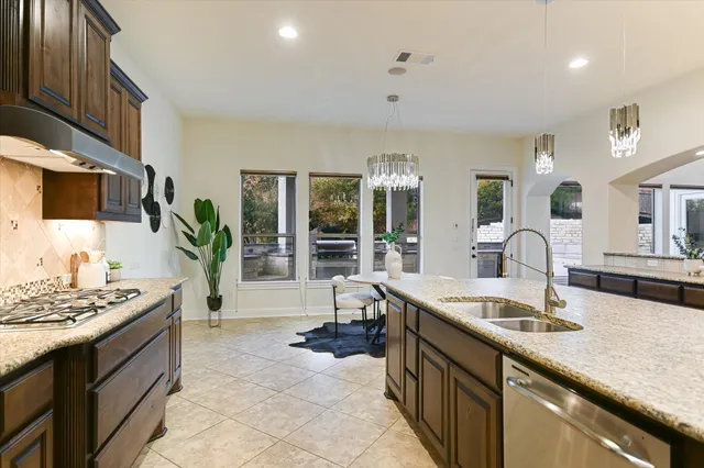 a kitchen with stainless steel appliances granite countertop a stove a kitchen island a dining table and chairs