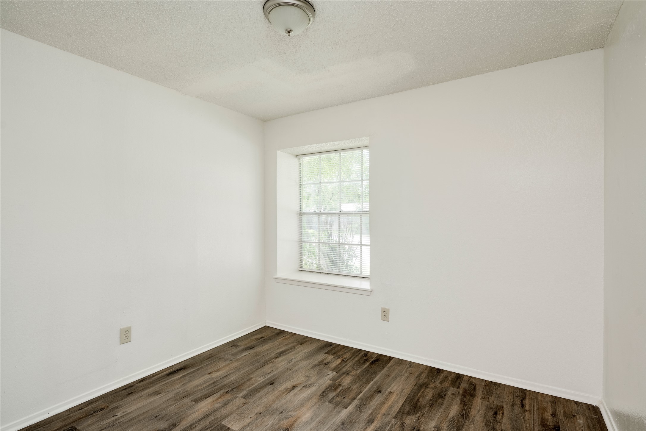 7918 West Gate Boulevard Austin, TX 78745 - Photo 3 of 31 Warm wood-look flooring and a naturally illuminated window define this comfortable bedroom space.