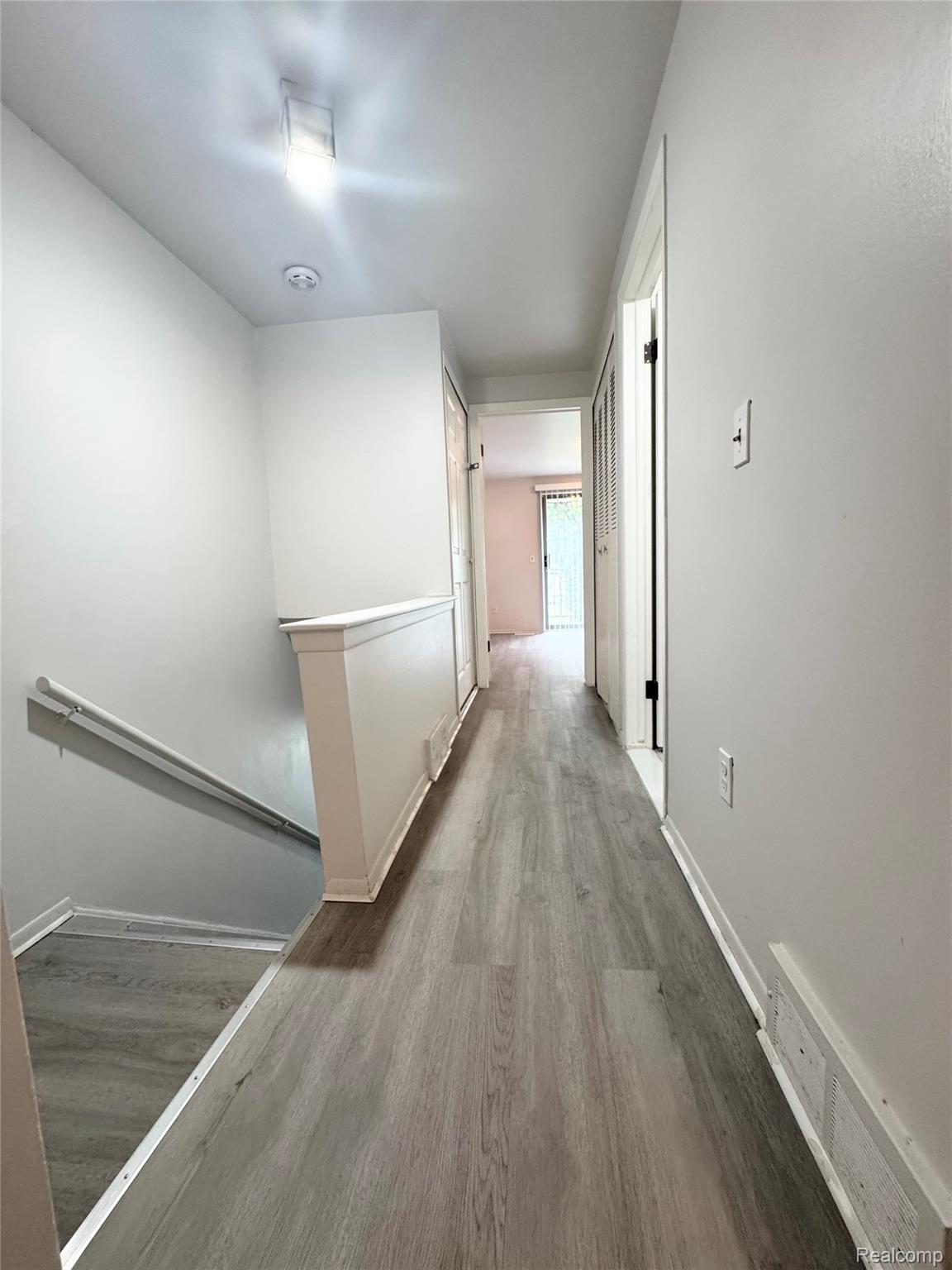 4386 15 Mile Road, Unit 64 Sterling Heights, MI 48310 - Photo 16 of 23 Hallway with wood-finish flooring, white painted walls, and ceiling-mounted lighting