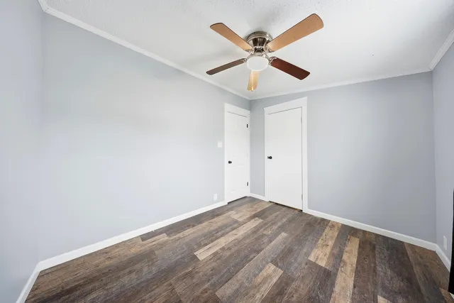 an empty room with wooden floor and ceiling fan