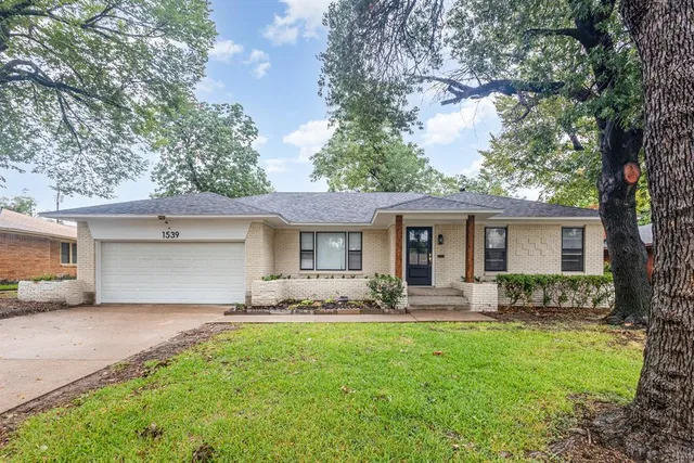 a front view of a house with yard and trees