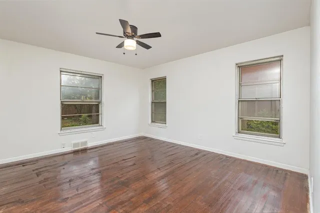 a view of an empty room with a window and wooden floor