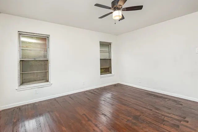 an empty room with wooden floor closet and windows