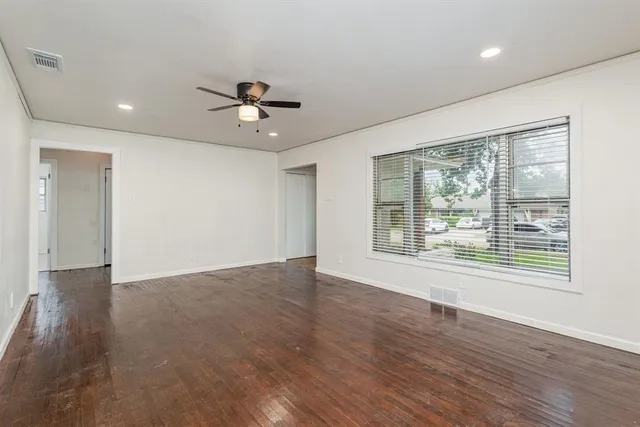 a view of an empty room with a window and wooden floor