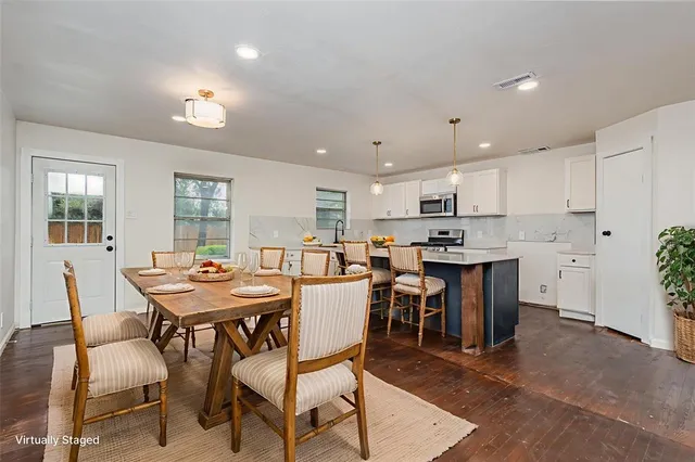 a dining room with stainless steel appliances kitchen island granite countertop a dining table chairs and a refrigerator