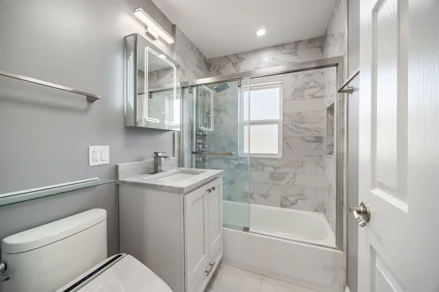 a bathroom with a granite countertop sink toilet and shower