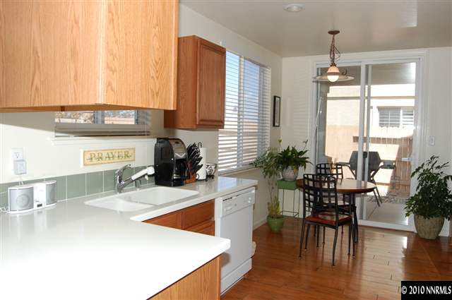 2175 Evergreen Park Drive Reno, NV 89521 - Photo 3 of 9 a kitchen with stainless steel appliances kitchen island granite countertop a stove a refrigerator a sink a dining table and chairs with wooden floor