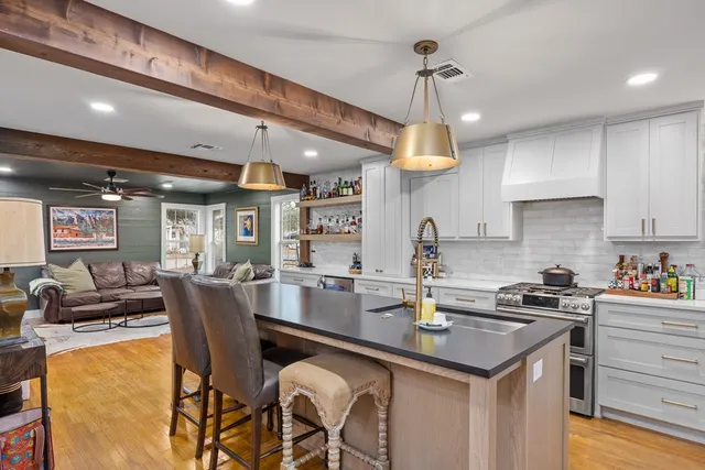 a kitchen with a dining table chairs sink and white cabinets