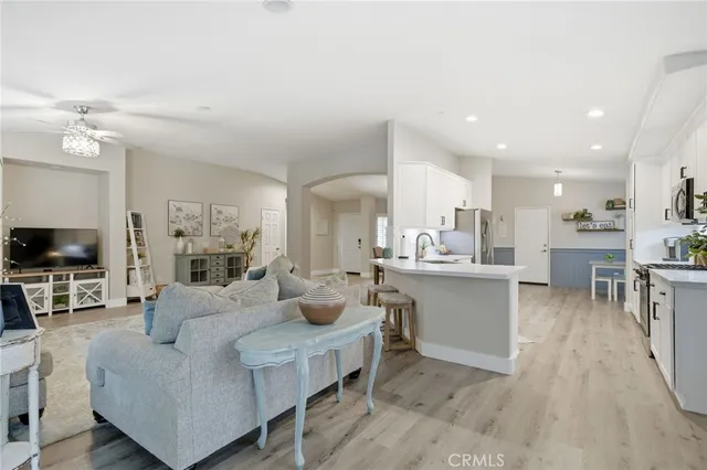 a living room with furniture a flat screen tv and kitchen view