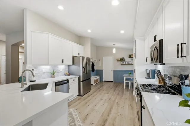 a large white kitchen with lots of counter space a sink appliances and cabinets