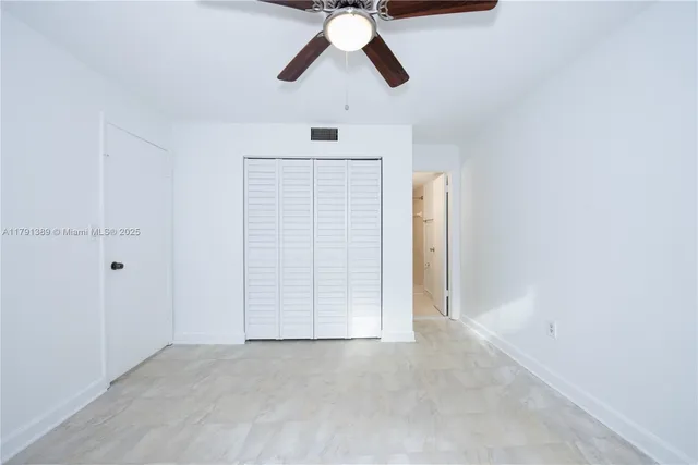 an empty room with ceiling fan and window