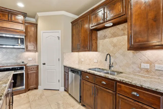 a kitchen with granite countertop stainless steel appliances a stove sink and cabinets