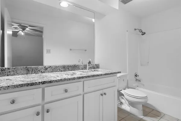 a bathroom with a granite countertop sink a toilet and a mirror