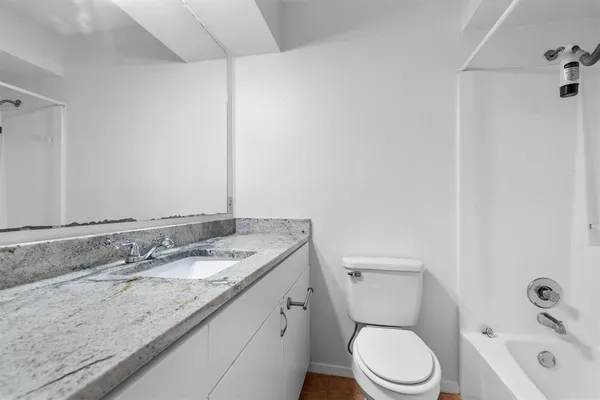 a bathroom with a granite countertop sink a toilet and a mirror