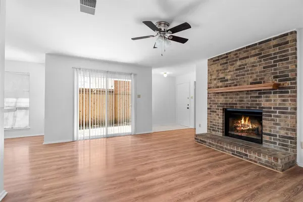 a view of an empty room with wooden floor fireplace and a window