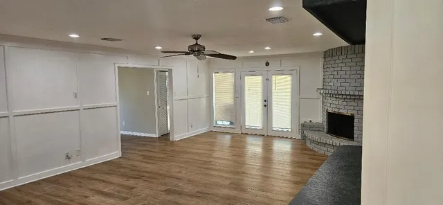 an empty room with wooden floor fireplace and windows