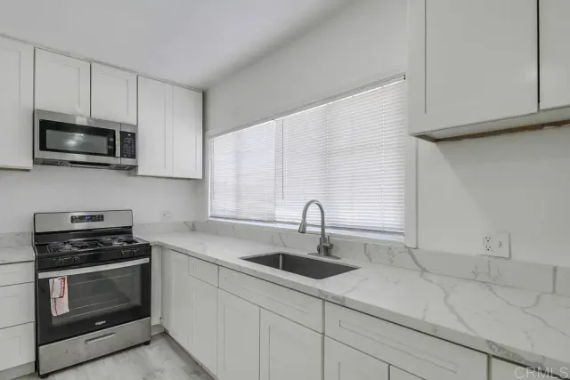 a kitchen with stainless steel appliances a stove a microwave a sink and cabinets