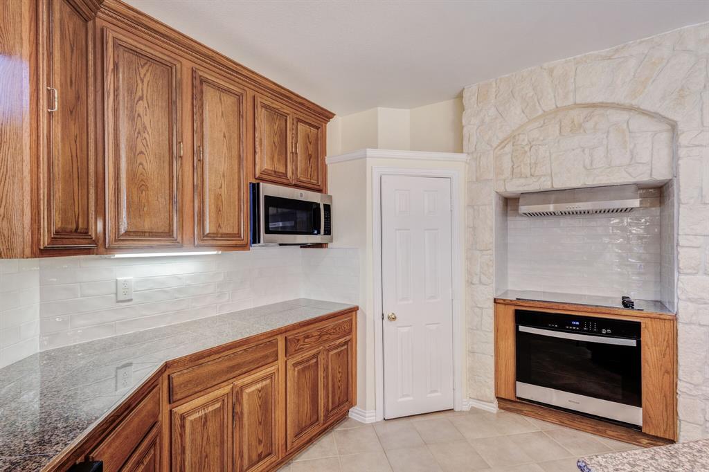 9618 Peach Tree Lane Rowlett, TX 75089 - Photo 25 of 40 a kitchen with stainless steel appliances granite countertop a stove microwave and refrigerator