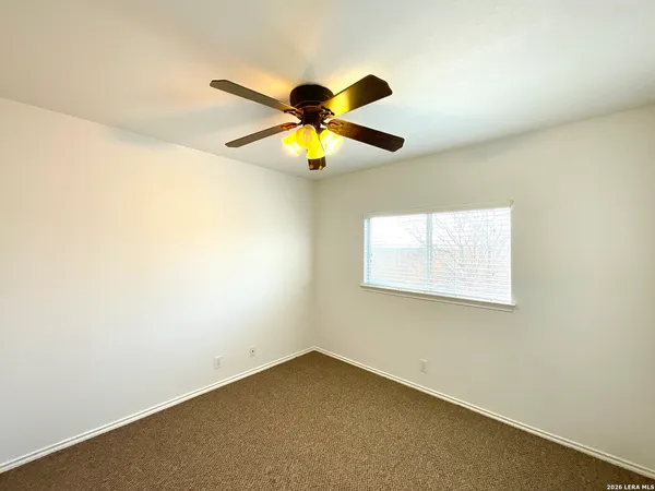 an empty room with a window and a fan