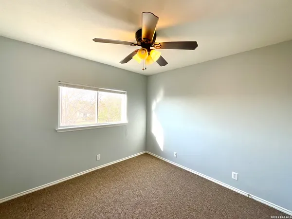 an empty room with ceiling fan and window