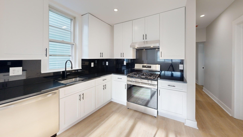273 Maverick Street, Unit 7 Boston, MA 02128 - Photo 25 of 26 a kitchen with granite countertop white cabinets and white appliances