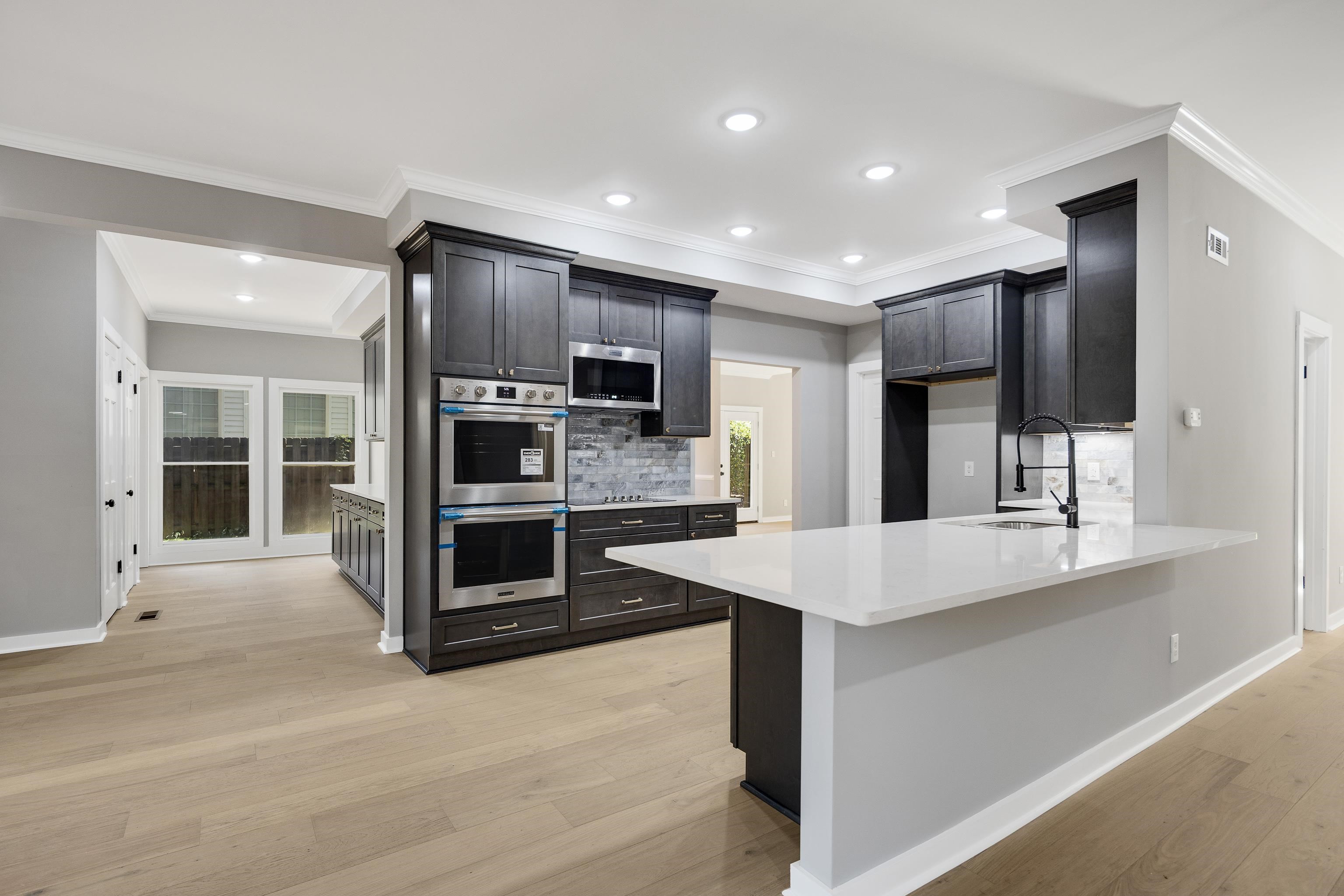 6380 Kirby Ridge Cove Memphis, TN 38119 - Photo 12 of 40 Kitchen with backsplash, light stone counters, crown molding, stainless steel appliances, and light wood-style floors