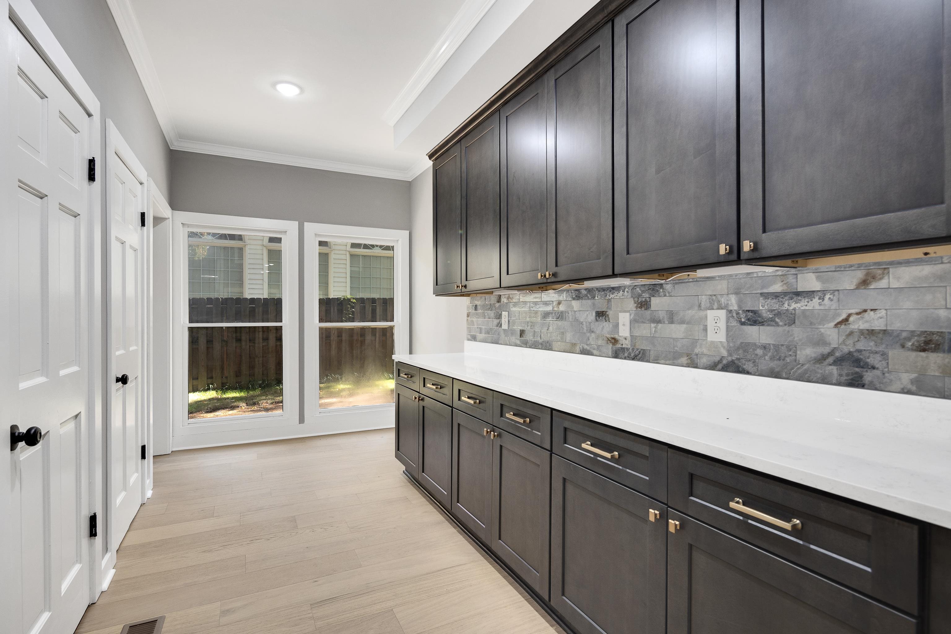 6380 Kirby Ridge Cove Memphis, TN 38119 - Photo 14 of 40 Kitchen featuring crown molding, decorative backsplash, light stone counters, and light wood-style floors