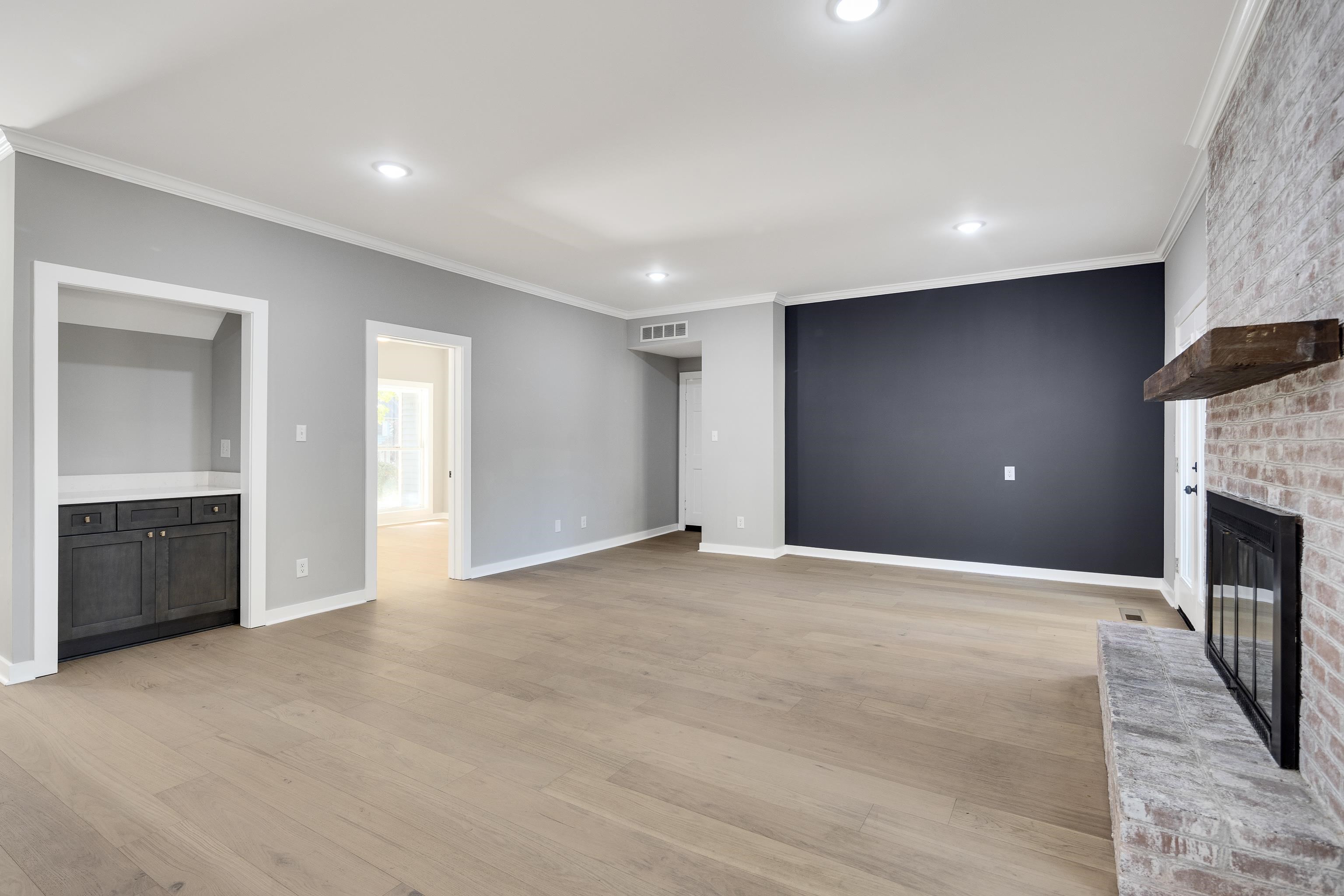 6380 Kirby Ridge Cove Memphis, TN 38119 - Photo 15 of 40 Unfurnished living room featuring crown molding, light wood-style floors, a brick fireplace, and recessed lighting