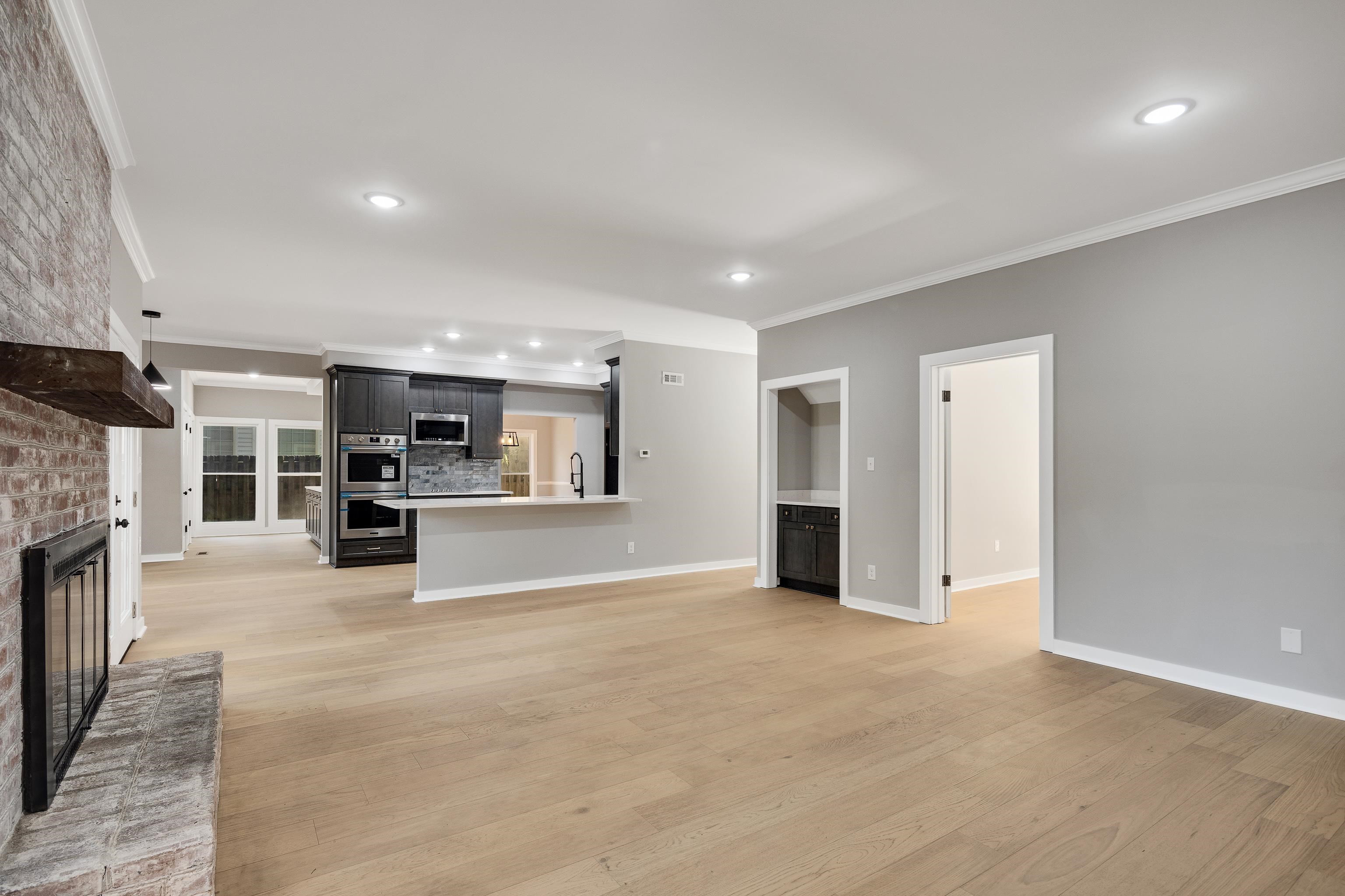 6380 Kirby Ridge Cove Memphis, TN 38119 - Photo 18 of 40 Unfurnished living room with ornamental molding, a brick fireplace, light wood-style floors, and recessed lighting