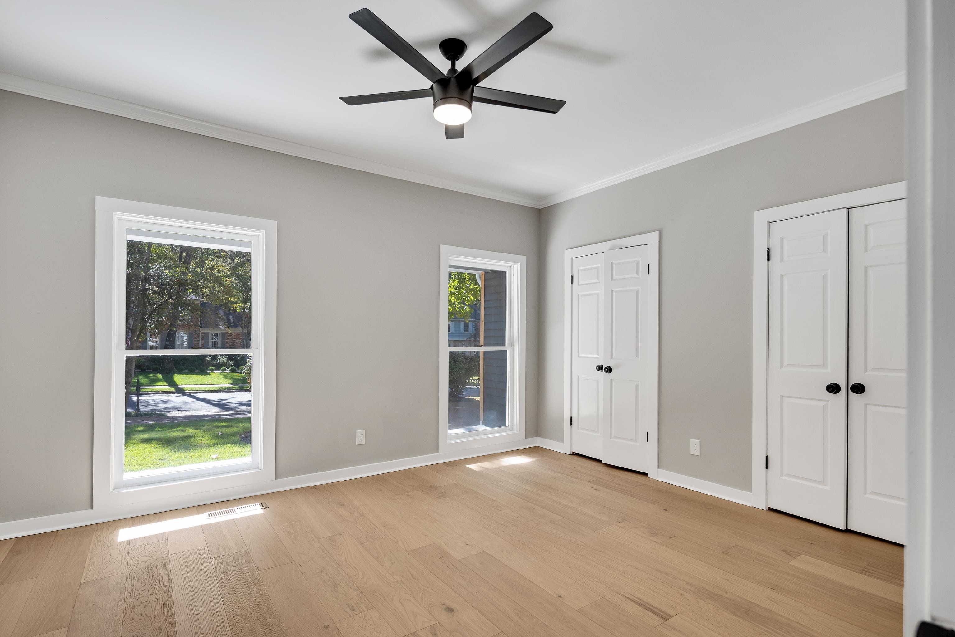 6380 Kirby Ridge Cove Memphis, TN 38119 - Photo 21 of 40 Unfurnished bedroom featuring multiple closets, ornamental molding, light wood-type flooring, and a ceiling fan