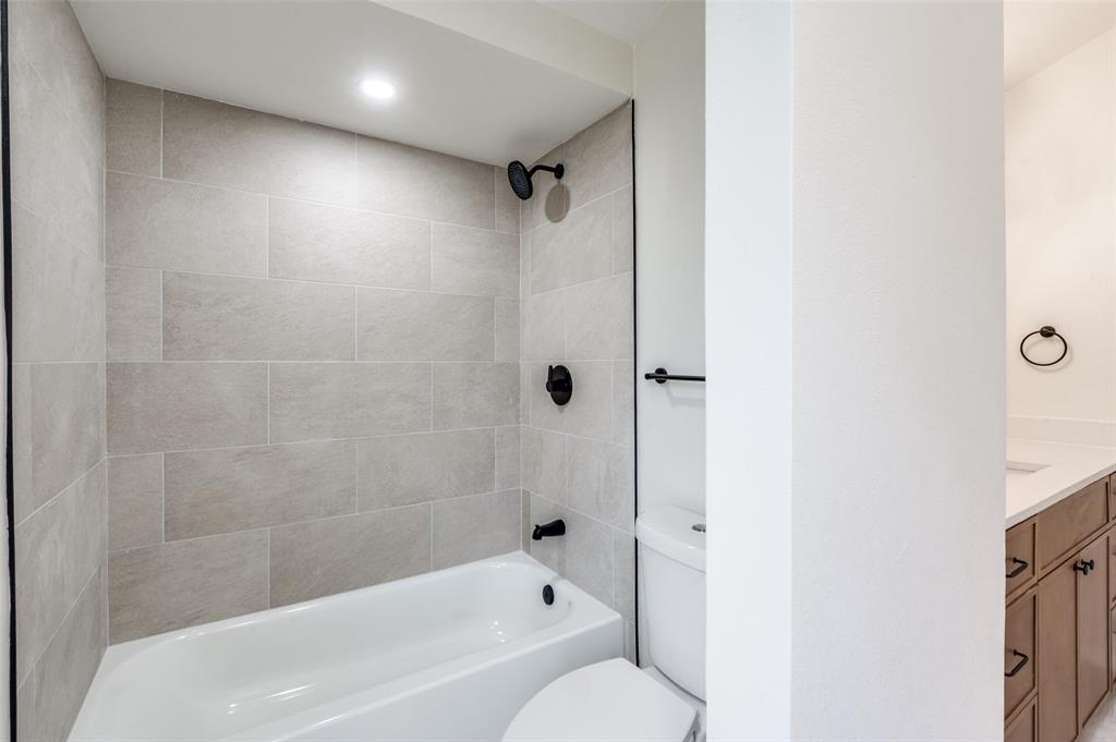 17490 Meandering Way, Unit 2202 Dallas, TX 75252 - Photo 22 of 24 Bathroom featuring a white bathtub, light-toned rectangular wall tiling, black fixtures, and a recessed ceiling light