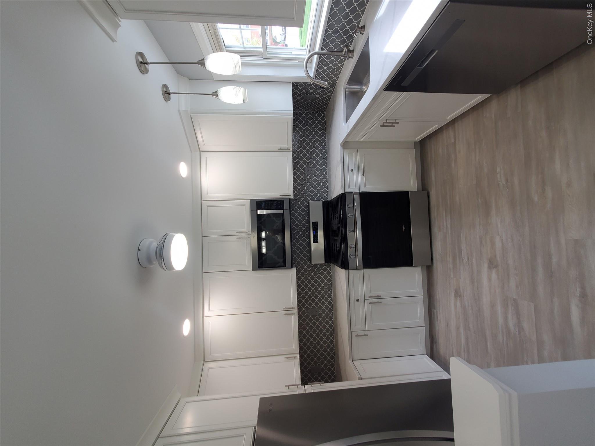 1879 Crompond Road, Unit A21 Peekskill, NY 10566 - Photo 6 of 20 a large kitchen with a stove a sink dishwasher a refrigerator and white cabinets with wooden floor
