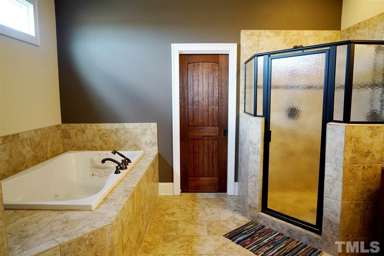 607 Competition Road Raleigh, NC 27603 - Photo 15 of 20 Master bath with large whirlpool, dual shower heads in shower, heated tile floor, door leading to walk-in closet