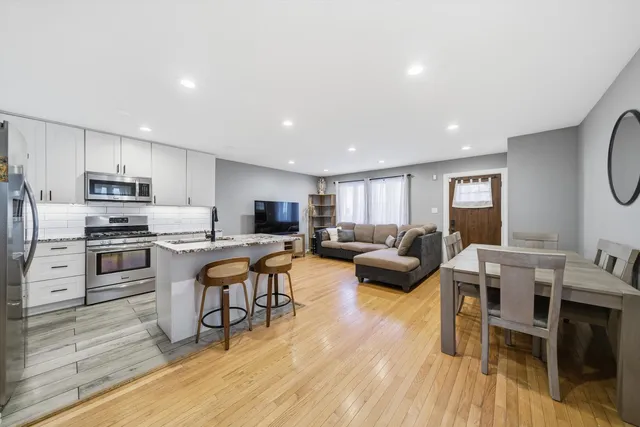 a living room with stainless steel appliances furniture and a wooden floor