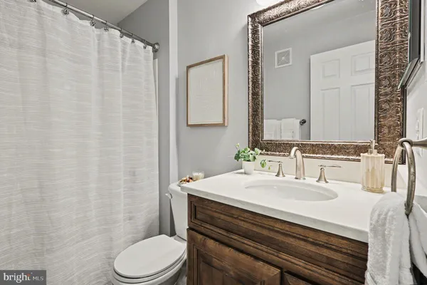 a bathroom with a sink a toilet a mirror and shower curtain