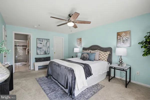 a spacious bedroom with a bed a couch and paintings on the wall