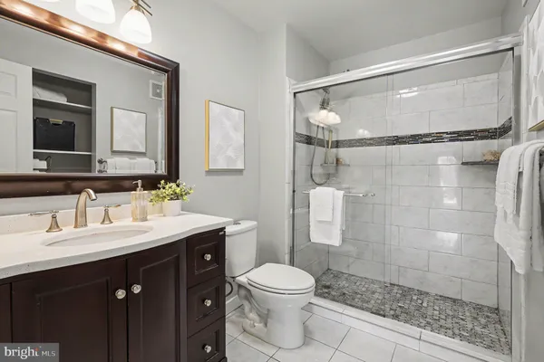 a bathroom with a granite countertop sink toilet a mirror and shower