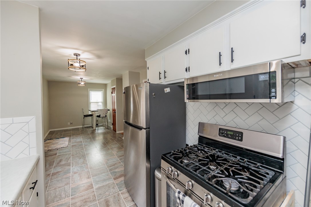 3206 Hearthstone Road Parma, OH 44134 - Photo 20 of 33 Kitchen featuring stainless steel appliances, light tile floors, white cabinetry, and backsplash
