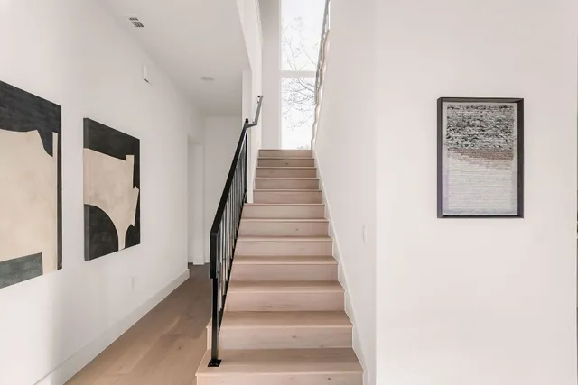 a view of staircase with lots of frames on wall and a large window
