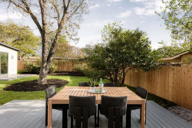 a view of a patio with table and chairs next to a yard with wooden fence