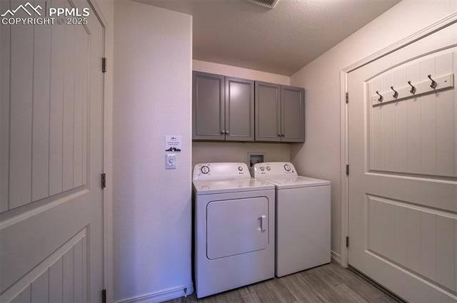 6604 Watusi Road Peyton, CO 80831 - Photo 19 of 40 Washroom featuring cabinet space, separate washer and dryer, light wood-type flooring, and a textured ceiling
