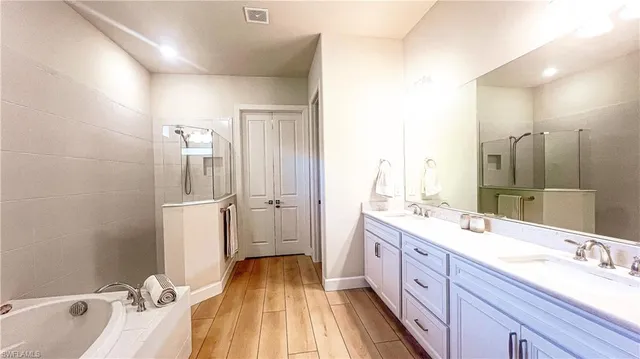 a spacious bathroom with a double vanity sink a mirror and a bathtub