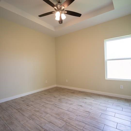 3052 Briggs Road, Unit C Weslaco, TX 78596 - Photo 8 of 16 Room with wood-finish tile flooring, tray ceiling, and a ceiling fan with integrated lighting